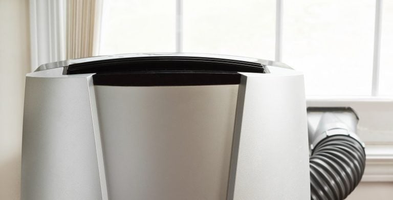 dual hose Portable air conditioner in front of brightly lit window.