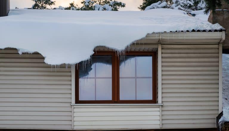 Thick layer of snow hanging off the edge of the roof.